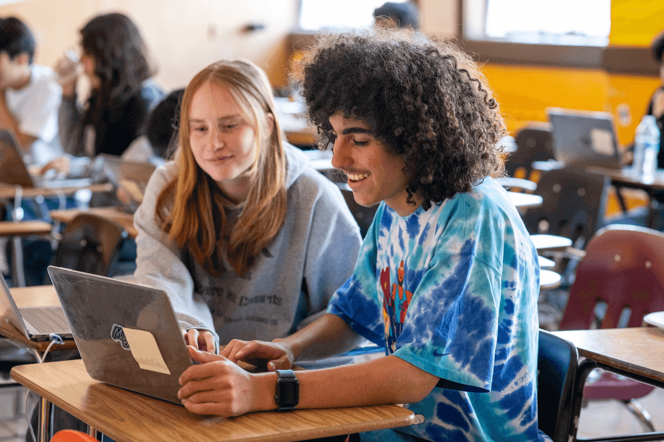 Two students working together on a laptop.