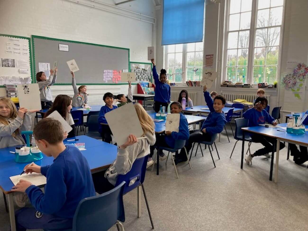 A group of schoolchildren working on small whiteboards.