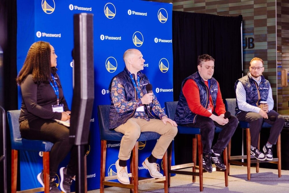 Four panelists seated in front of a branded 1Password and Golden State Warriors backdrop.