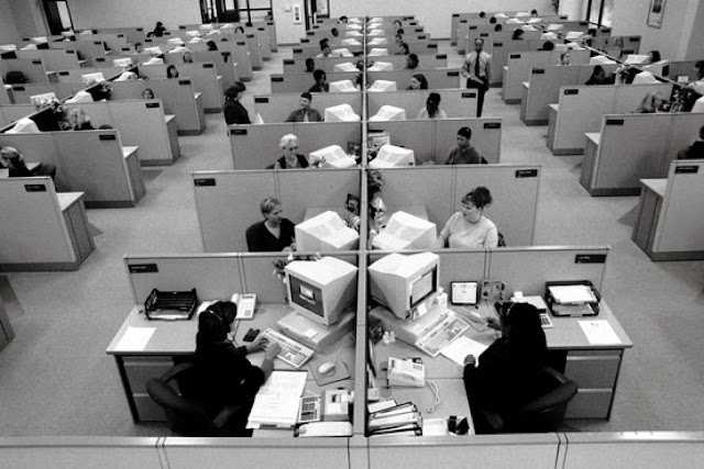 A black and white photo of a cubicle farm.